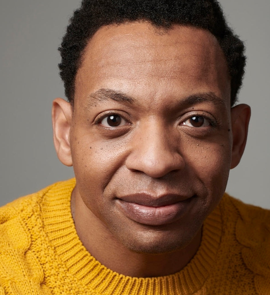 Man wearing a yellow sweater against a gray background
